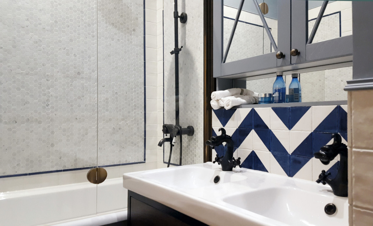 В ванной комнате уместили сдвоенную раковину с двумя смесителями. Стены облицевали мраморной мозаикой и керамогранитной плиткой.